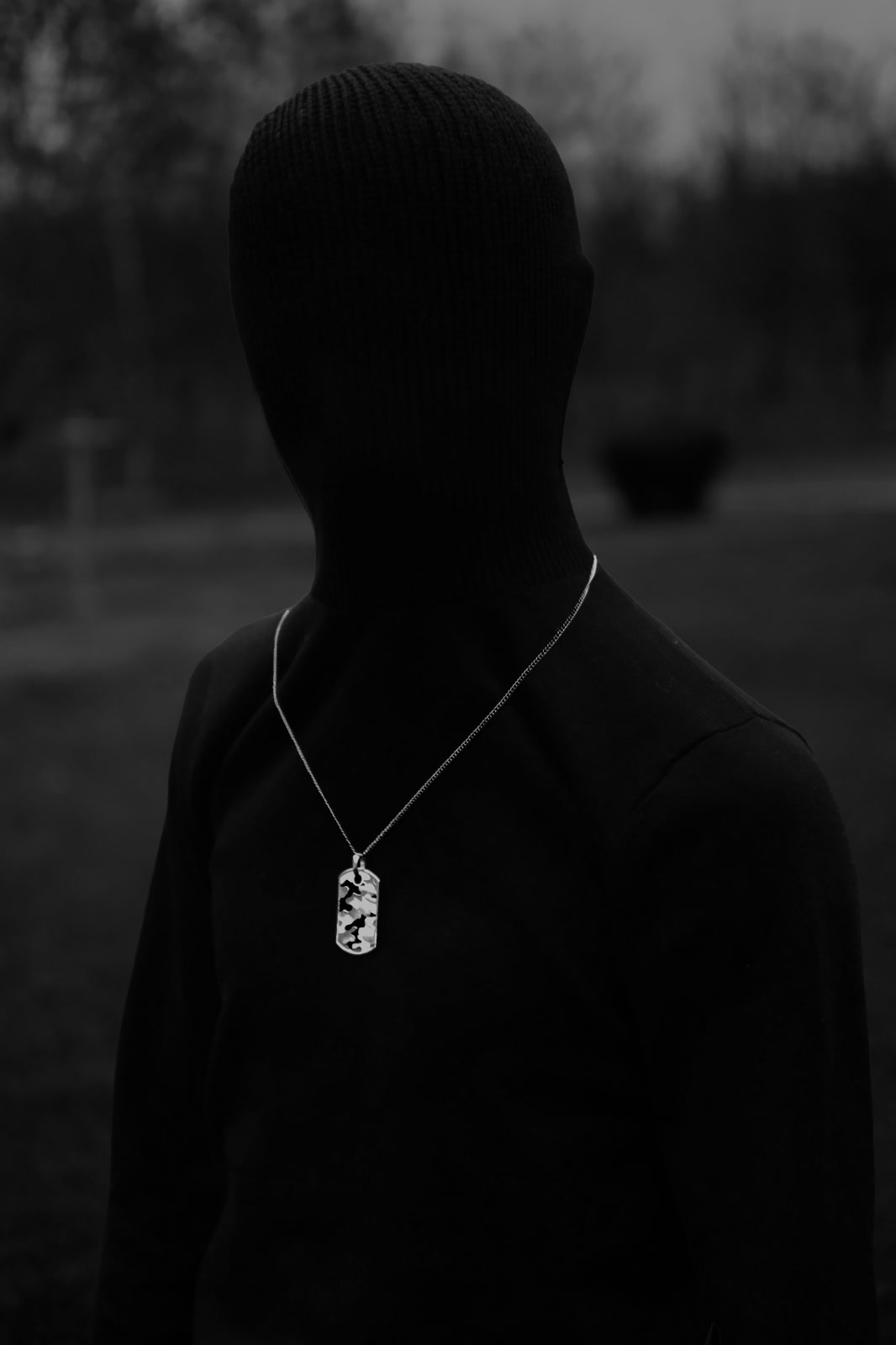 Low-key portrait, figure in black wearing a pendant