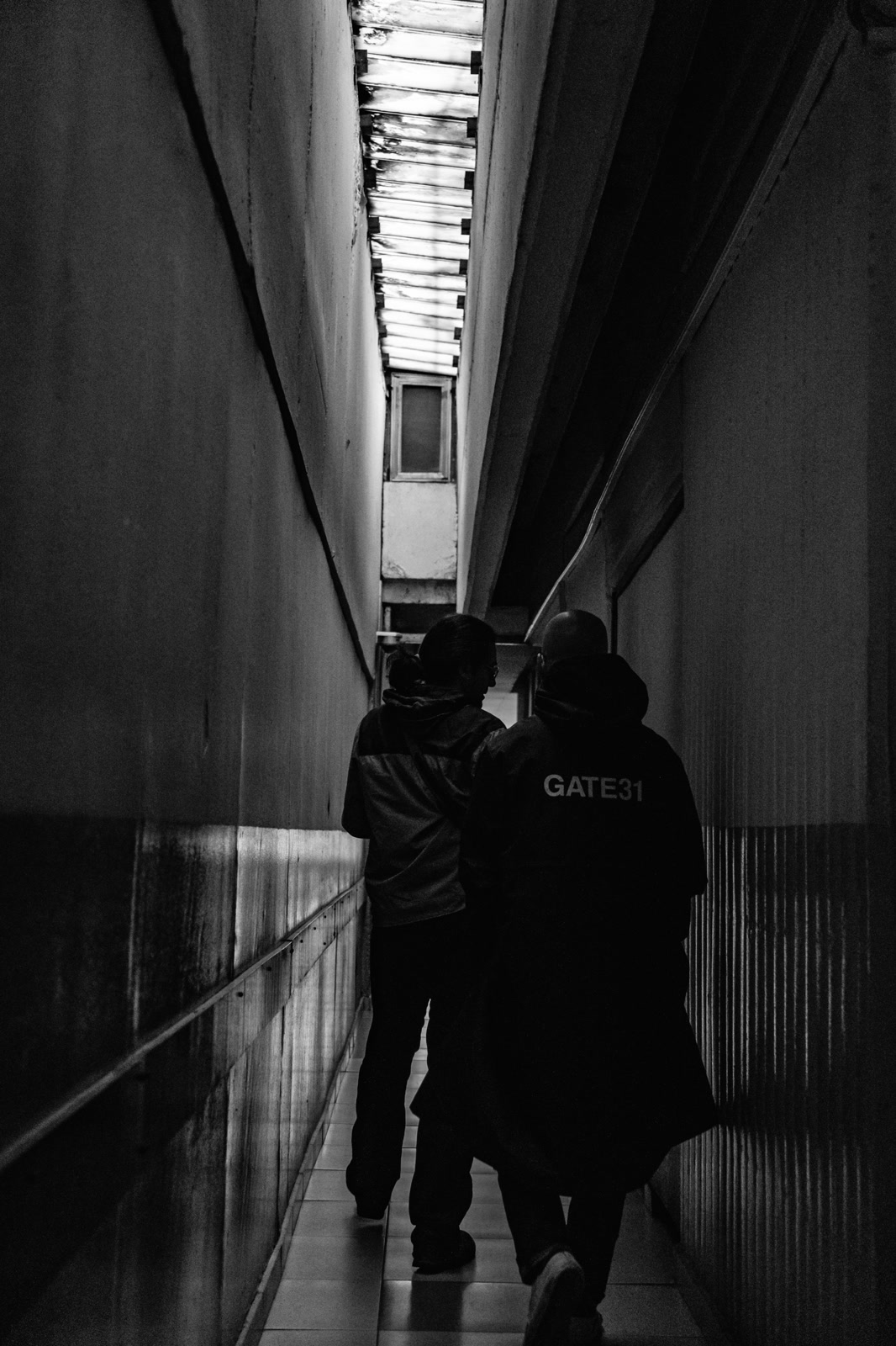 Two figures walking a concrete underpass