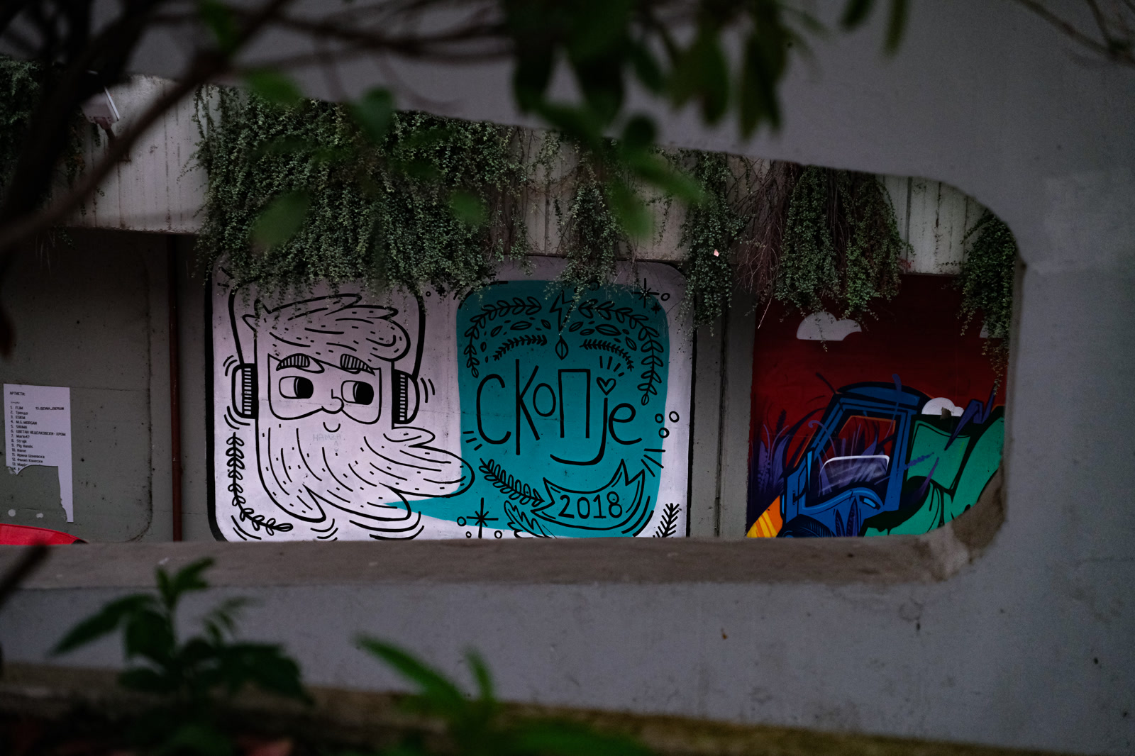 Graffiti on a concrete wall behind hanging leaves