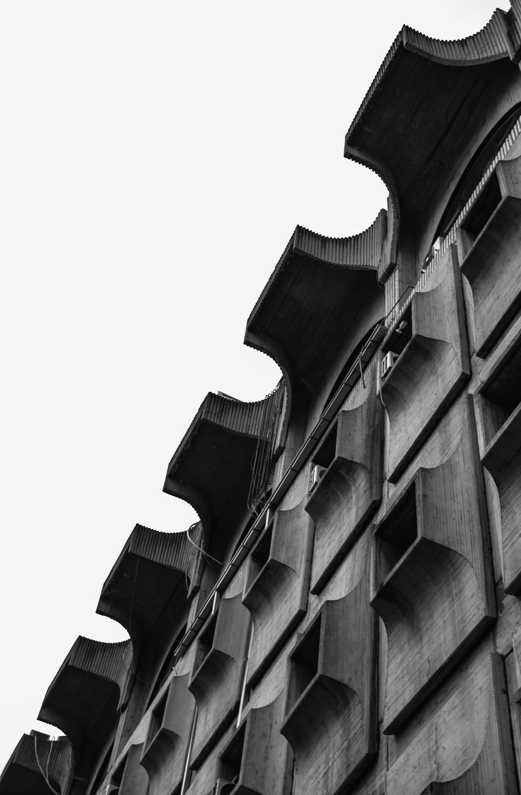 Scalloped concrete balconies against a white sky