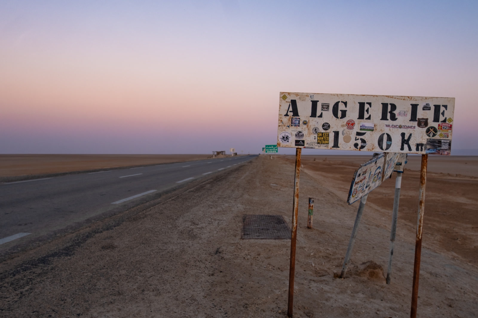 Road sign reading Algerie 150 km at dawn